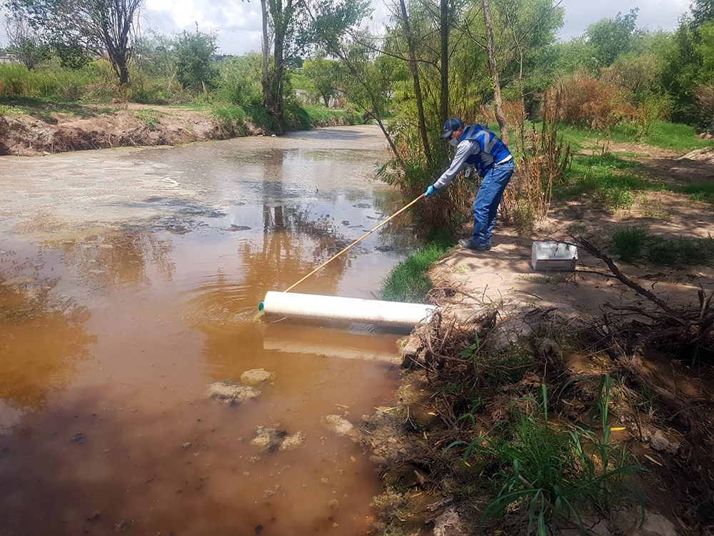 tecnico ambiental realiza muestreo en agua de rio