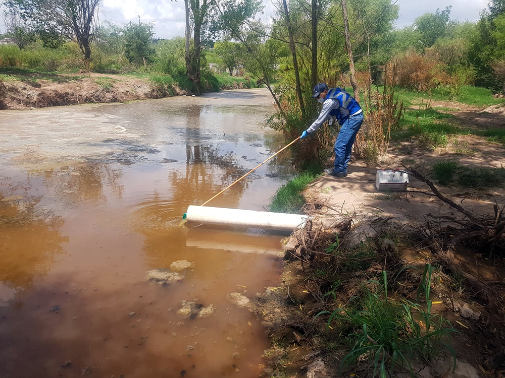 tecnico ambiental realiza muestreo en agua de rio